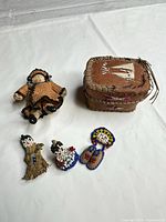 Group shot of all five items: crochet doll, birchbark basket, two beaded dolls, beaded moccasins