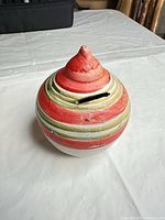 Front view of ceramic coin bank showing stripes and coin slot