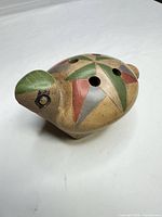 Angled view of turtle ocarina showing top finger holes and painted geometric motifs