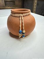 Front view showing round terracotta pot and beaded cord trim