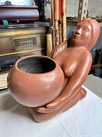 Front view showing figure holding pot planter
