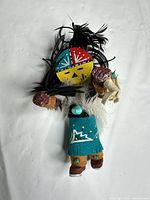 Front view of Kachina doll showing mask, feathers, suede clothing