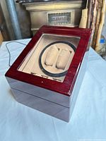 perspective view of burgundy lacquered wood watch winder showing acrylic window and interior cushions