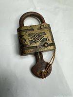 Front view of brass padlock showing pattern and S emblem