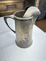 Left side view of tarnished silver-plated pitcher with handle and spout cover