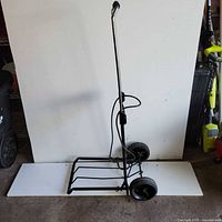 Full side view of folded luggage cart showing frame and wheels