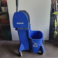 Front view of blue Ecolab mop bucket with wringer and wheels
