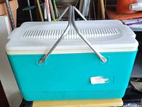 Front view of teal Rubbermaid cooler with handles up