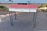 Full view of table showing red top, chrome legs, drawer