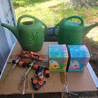 Overall lot showing both watering cans, sprinklers, hose fittings, and boxed traps