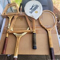 Group shot of four wooden tennis rackets on cardboard, two in presses, Slazenger head cover visible