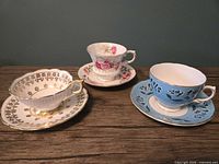 Three teacup and saucer sets displayed