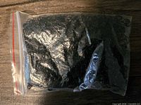 Sealed plastic bag filled with black metal teardrop clips