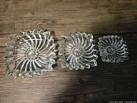Top view of three clear pressed glass dishes showing pattern and relative sizes