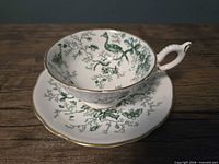 Side view of teacup on saucer showing pattern and gold trim