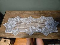 Full view of light blue hand-crocheted cotton table runner on wood surface