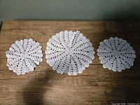 Three light blue crocheted doilies displayed on wooden surface