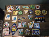 Full lot of 25 embroidered scouting patches arranged on table