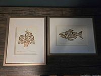 Both framed Bill Reid gold foil prints on table