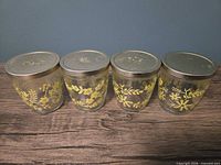 Four jars side by side showing lids and floral design