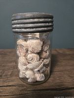 Front view of glass Crown jar filled with sea shells