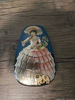 lid showing Victorian lady, bouquet, dog imagery on blue background