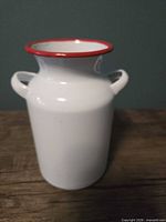 Front view showing white enamel milk can with red rim and handles