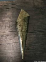 Front view of brass wall-mounted incense holder showing embossed design and mounting hole