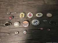 Assorted brooches and stick pins arranged on wood surface