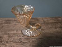 Left-front view of amber pressed glass cornucopia vase