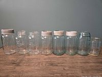 Line of eight assorted vintage mason jars on wooden surface