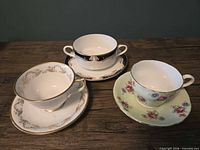 Three Aynsley teacup and saucer sets on table