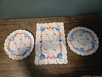 Full view of three scalloped-edge floral cotton linens on table