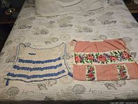 Both aprons laid out on bed showing full design and size