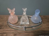 Front view of three perfume bottles on oval glass tray