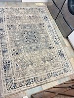 Full view of rectangular gray and blue distressed rug on tile floor