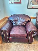 Front view of burgundy leather armchair showing overall design and nailhead trim