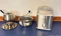 Ice cream maker, food mill and fondue pot displayed side by side on counter