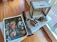 Overview showing poster, two pulley blocks, wooden crate with metal dividers, and leather bell strap