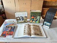 Entire lot on table showing Darwin book, dictionary, open pages, boxed set, stack of magazines