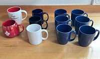 All eleven mugs arranged on countertop showing colours and logos