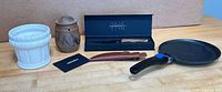All items: skillet with handle, Motsoto knife in box with sheath, white ceramic planter, brown earthenware jar