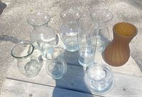 Eight vases displayed on outdoor table, full lot overview