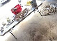 Overview of table with assorted cables, rope, red crate containing small desk lamp and hardware buckets