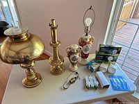 Five lamp bases, glass chimney, hardware and bulb packages displayed on table
