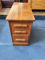 Front view showing three drawers and handles