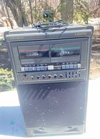 Front view showing Optimus branding, twin cassette decks, equalizer sliders, microphone jacks and speaker grille