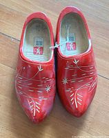 Top view of both red wooden clogs showing decorative pattern and overall condition