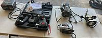 Overview of router, jigsaw, cordless drill with case, charger on table