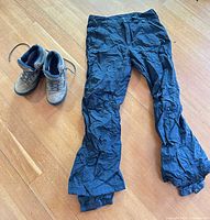 Boots and ski pants laid out on floor